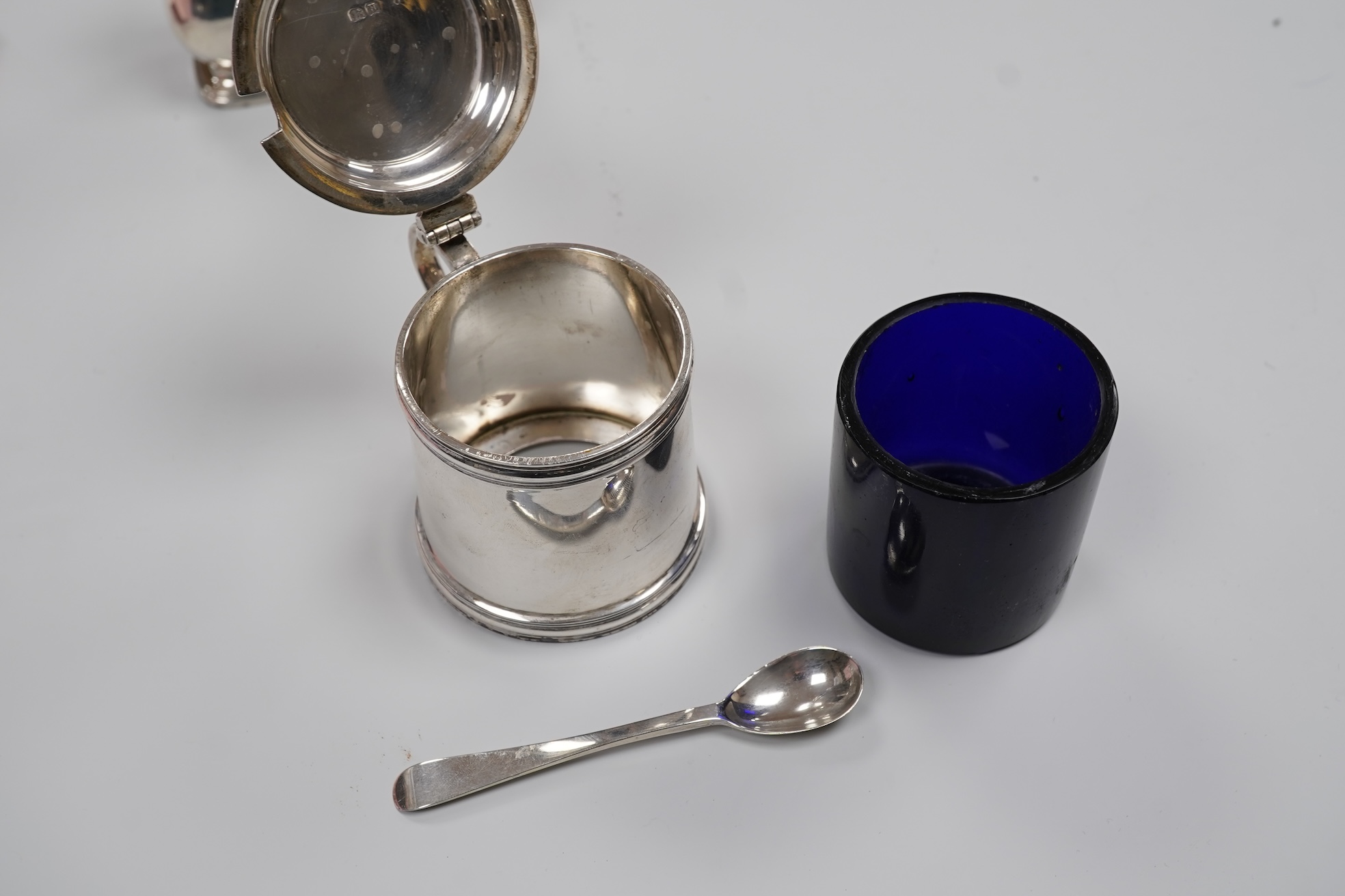 A George V silver drum mustard by Mappin & Webb, Birmingham, 1923, height 71mm, with associated spoon, together with a pair of George V silver pepperettes, Adie Brothers, Birmingham, 1923.
